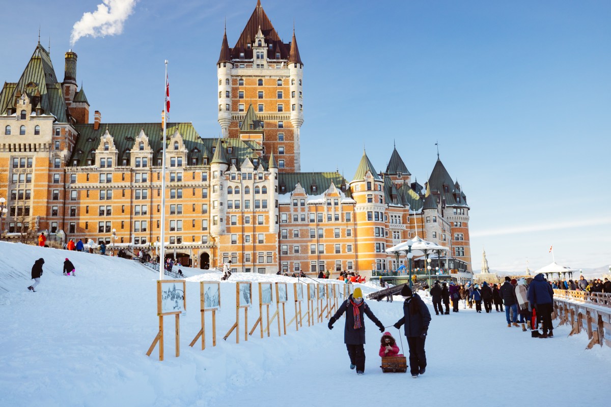 Snowy scene with people in front of a large castle-like building in winter.