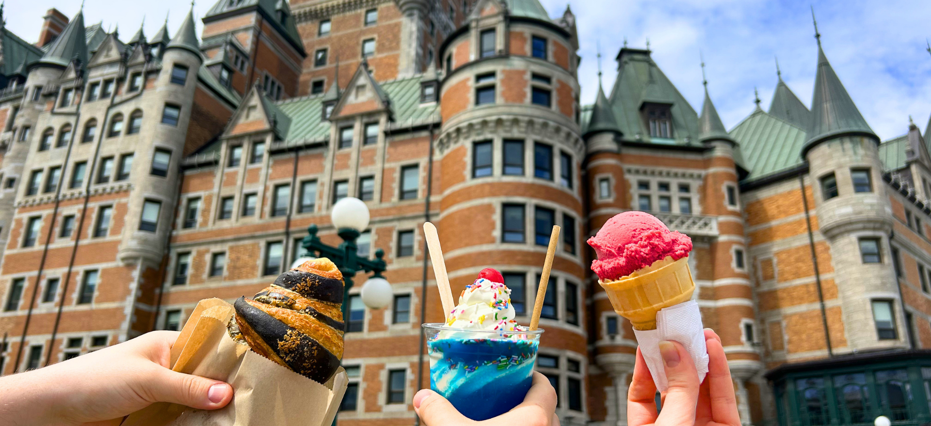 Three hands holding ice creams in front of a castle-like building.