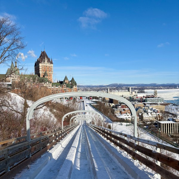 Snowy toboggan slide with Château Frontenac in the background under a clear blue sky.